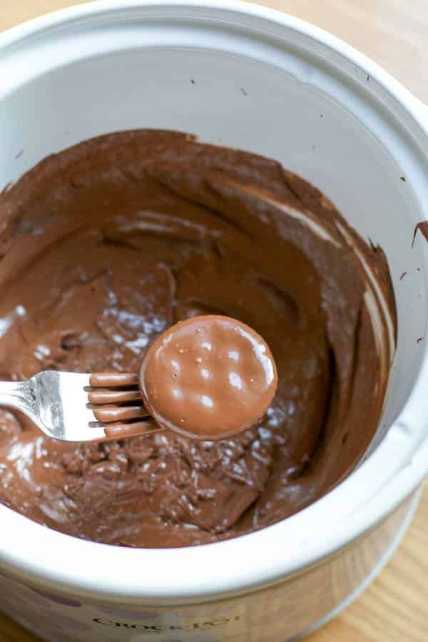 Ritz cracker being dipped into mint chocolate in round slow cooker