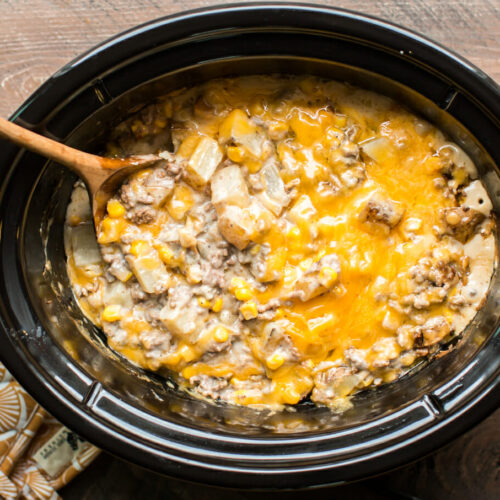 hamburger hash in slow cooker with wooden spoon in it.