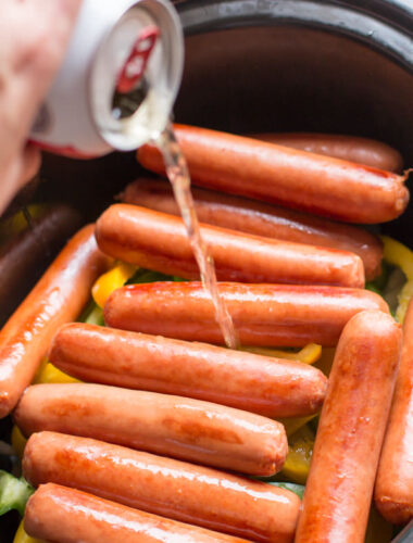 beer being poured over brats in slow cooker.