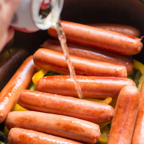 beer being poured over brats in slow cooker.