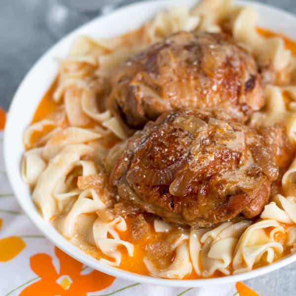 2 chicken thighs on egg noodles in bowl.