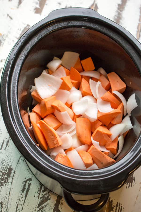 raw sweet potatoes and onion in slow cooker