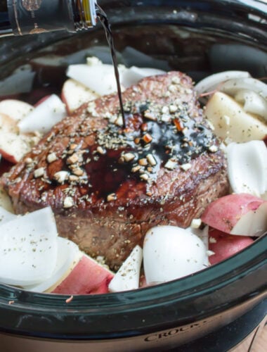 balsamic being poured over a beef roast in slow cooker