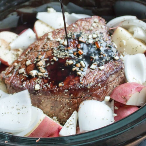 balsamic being poured over a beef roast in slow cooker