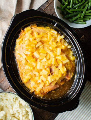 pineapple ham in slow cooker with mashed potatoes and green beans on the side.