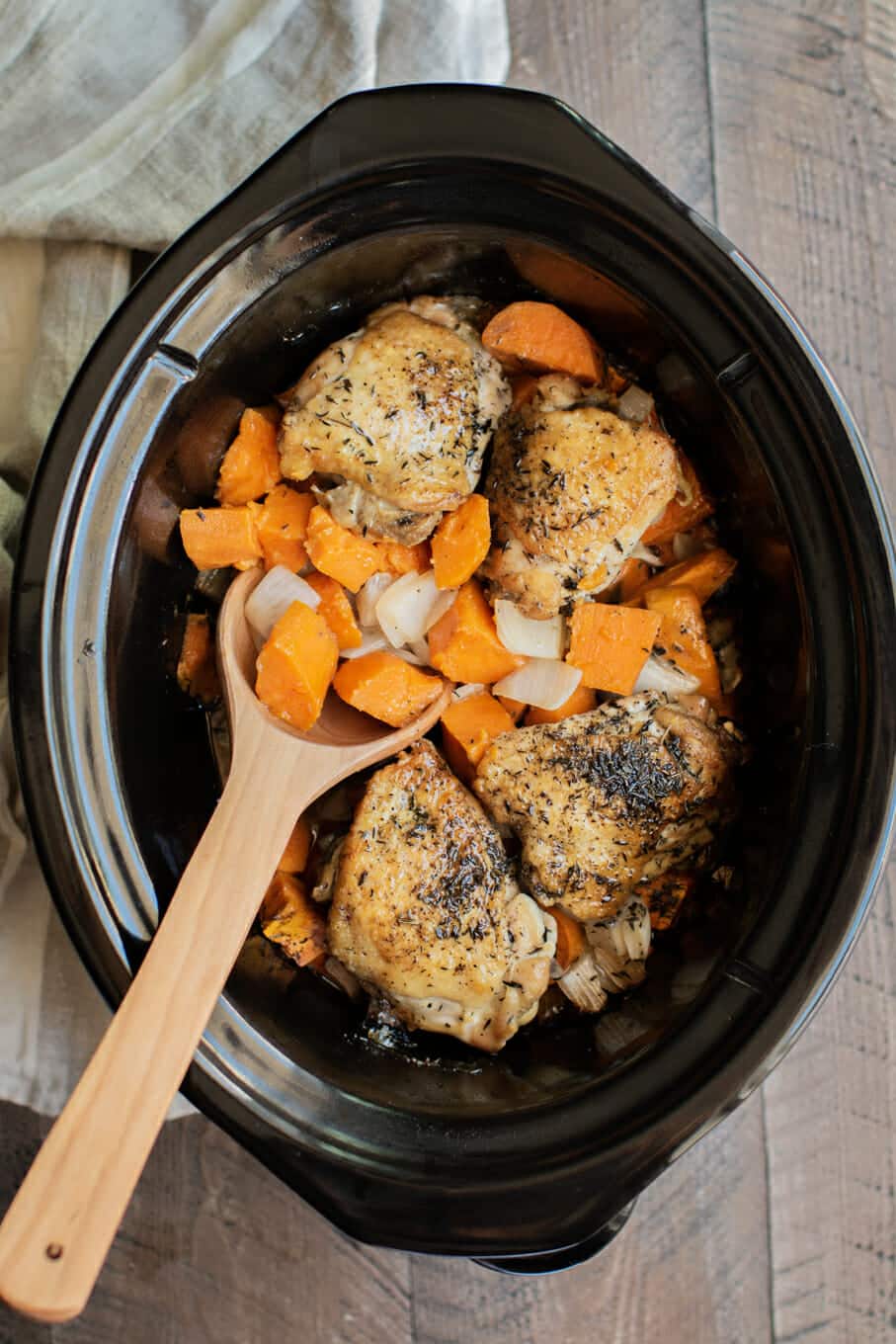 Cooked chicken thighs, sweet potatoes and onions in slow cooker.