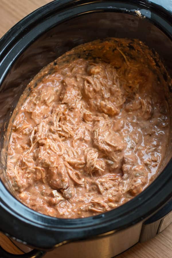Shredded chicken with sauce in slow cooker.