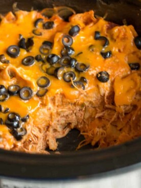chicken enchilada casserole in slow cooker with scoop missing.