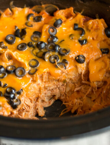 chicken enchilada casserole in slow cooker with scoop missing.