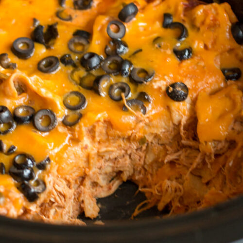 chicken enchilada casserole in slow cooker with scoop missing.