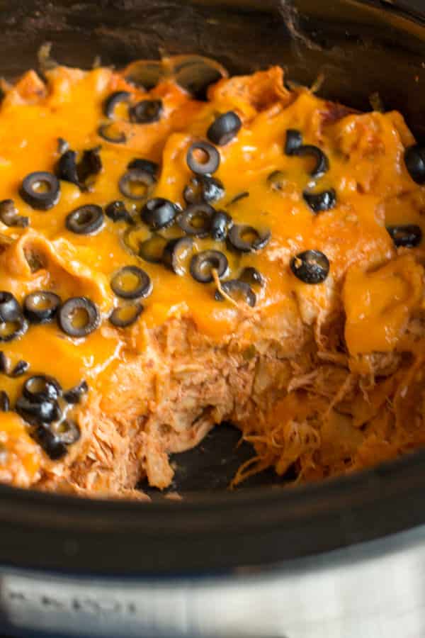 chicken enchilada casserole in slow cooker with scoop missing.