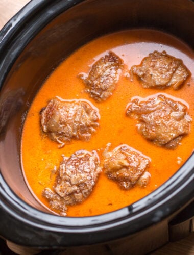 Chicken thighs in bright orange paprika sauce in slow cooker
