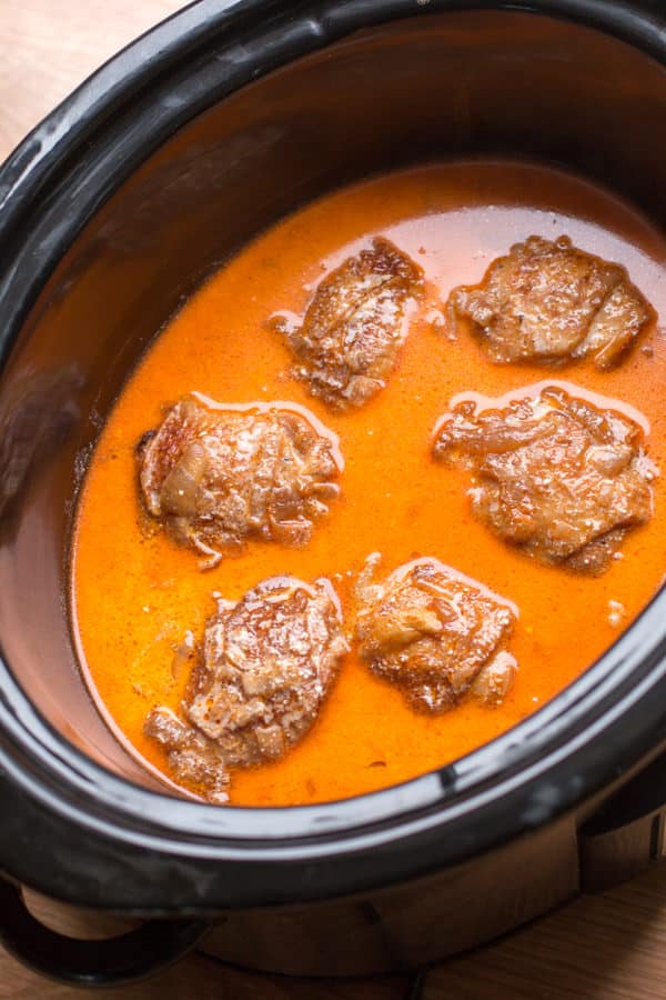 Chicken thighs in bright orange paprika sauce in slow cooker