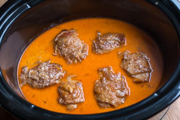 Six skin-on chicken thighs in paprika sauce in slow cooker.