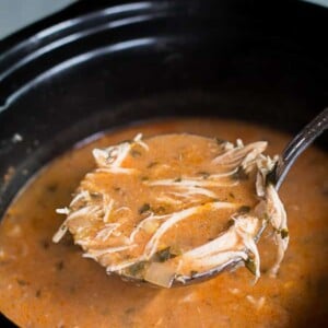 chicken enchilada soup in slow cooker with ladle scooping it out.