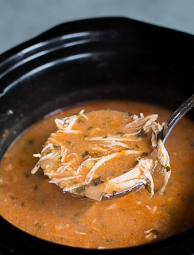 chicken enchilada soup in slow cooker with ladle scooping it out.