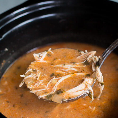 chicken enchilada soup in slow cooker with ladle scooping it out.