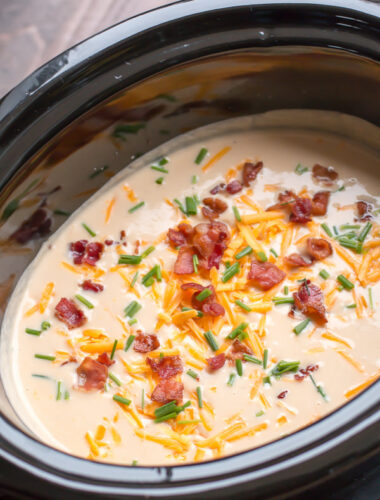 Creamy cauliflower cheese soup with bacon, chives and cheese on top.