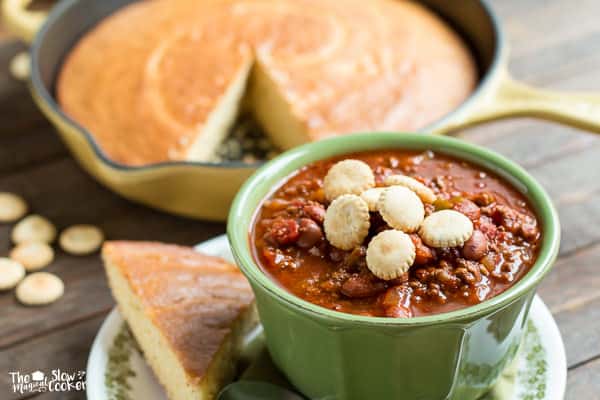 chuck wagon chili in bowl with cornbread on side and oyster crackers on top.