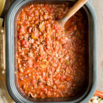 beef chili in a slow cooker with spoon in it.