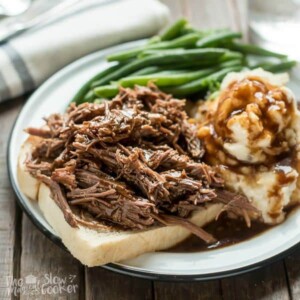 shredded beef and gravy over white bread on a plate.
