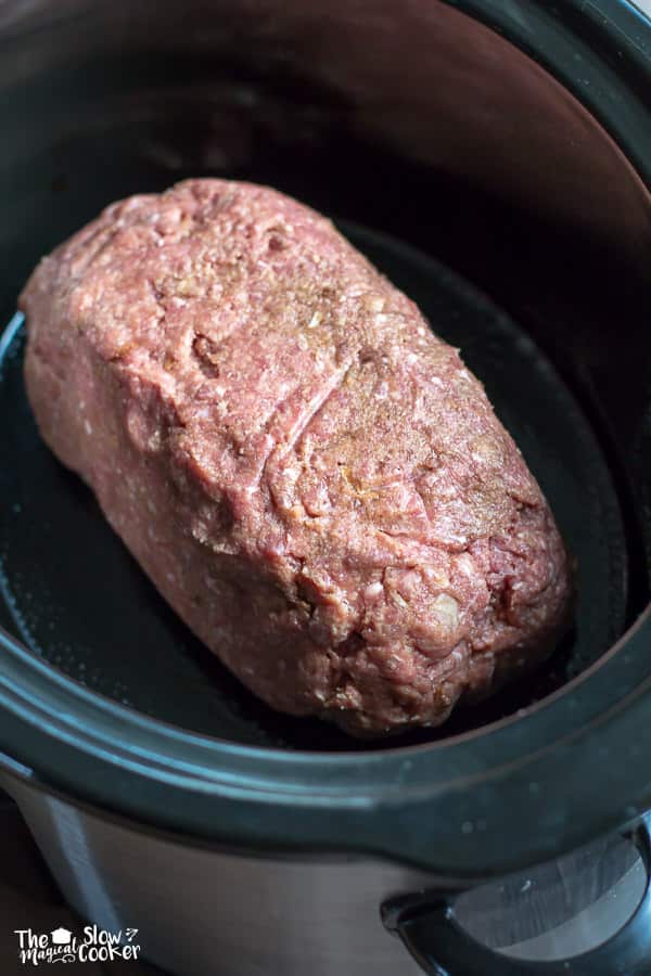 Onion meat loaf mix shaped into a loaf form in slow cooker.
