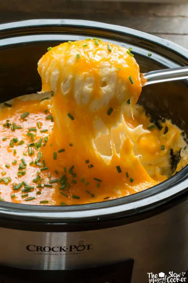close up of cheesy potatoes being scooped on a metal spoon.