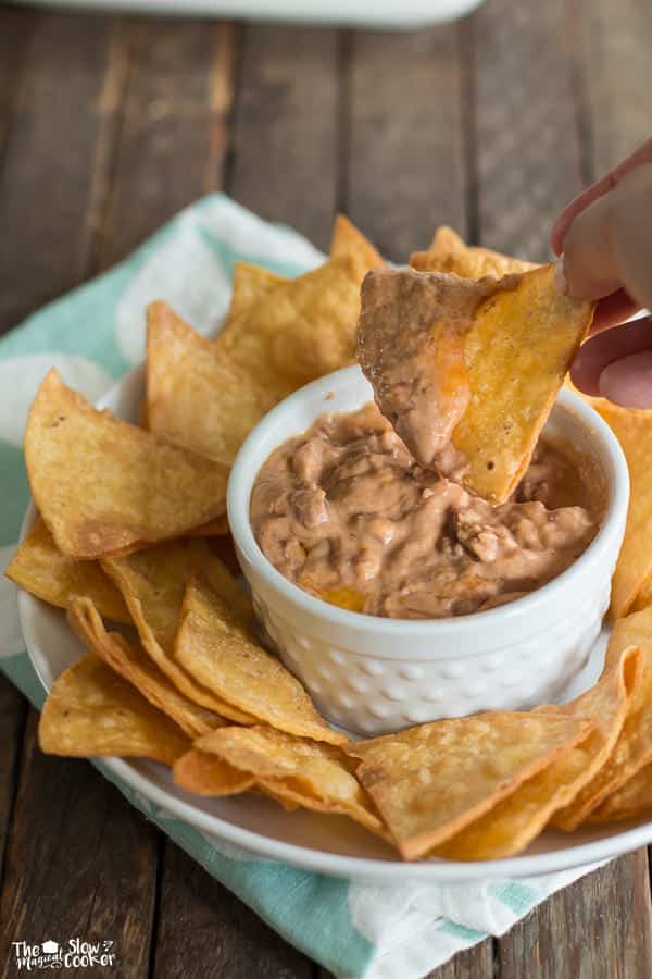 chip being dipped in small white ramekin.