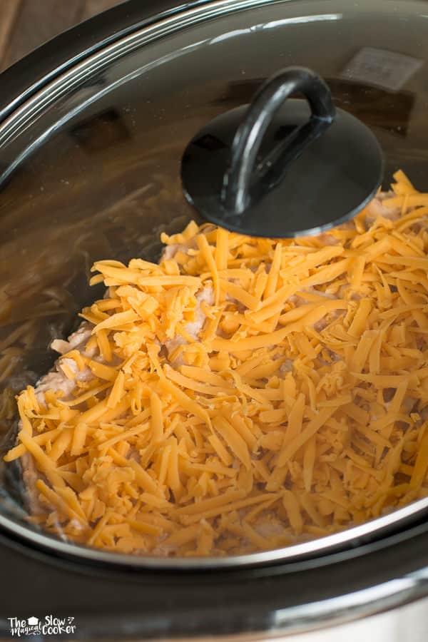 Bean dip with cheese on top with lid on slow cooker.