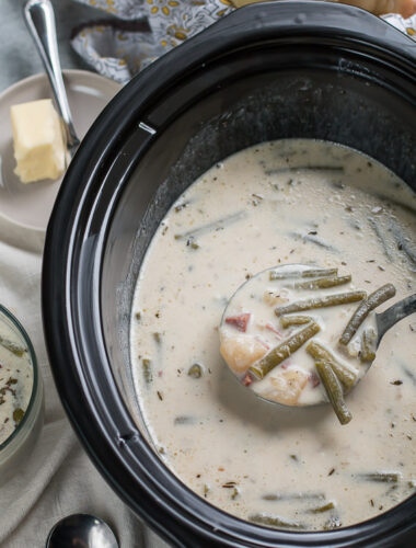 ladle of ham and green bean chowder coming from slow cooker