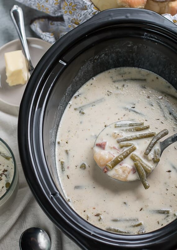 ladle of ham and green bean chowder coming from slow cooker