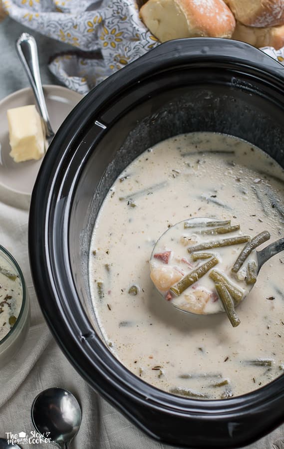 ladle of ham and green bean chowder coming from slow cooker