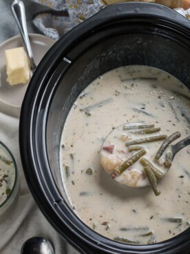 scoop of green bean chowder coming from slow cooker.