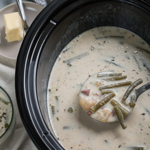 scoop of green bean chowder coming from slow cooker.