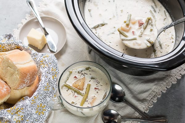 Bowl of green bean and ham chowder with slow cooker on side.