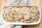 platter of fettuccine noodles in creamy sauce with pork chops on top