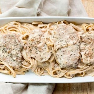 platter of fettuccine noodles in creamy sauce with pork chops on top