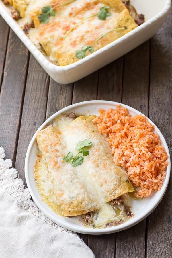 plate with 2 enchiladas on it and Mexican rice on the side.