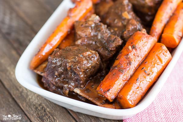 close up of short ribs and carrots in white platter