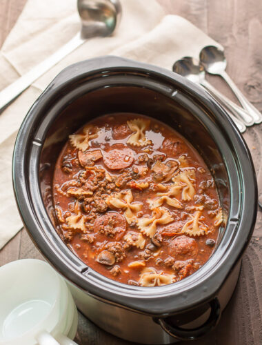 slow cooker with pizza soup in it, ladle and spoons on side