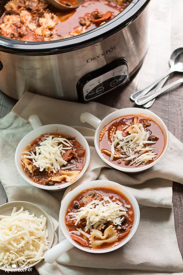 Three white bowls of pizza soup with mozzarella on top.