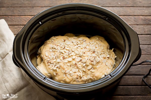 Almonds on top of cream of chicken soup and chicken in slow cooker.