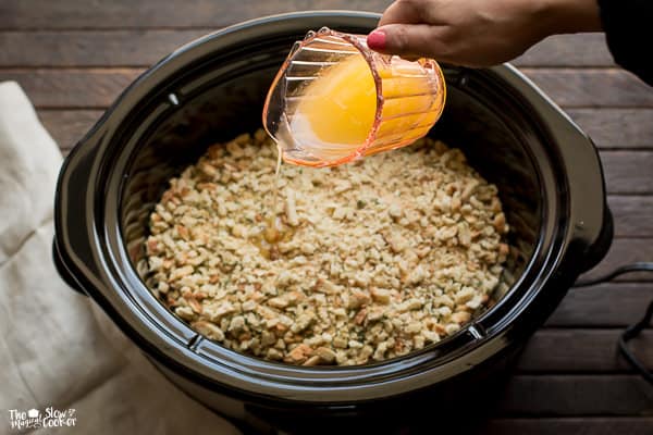 Butter being poured over chicken and stuffing in a slow cooker.