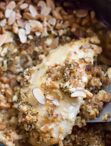 close up of chicken breast with stuffing and almonds on top.