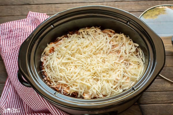 Spaghetti in slow cooker with mozzarella cheese on top.