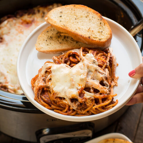 plate with baked spaghetti with cheese, garlic butter on the side.