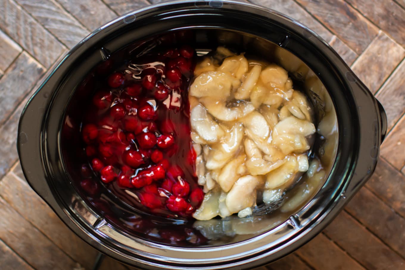 Cherry pie filling on one side of slow cooker and apple pie filling on the other side.