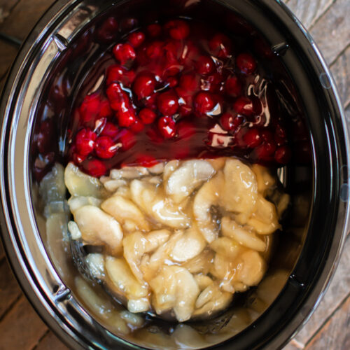 cherry pie filling on half of slow cooker and apple on the other half.