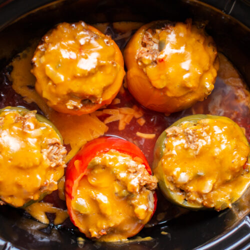 5 meatloaf stuffed peppers with cheese on top in slow cooker, in salsa