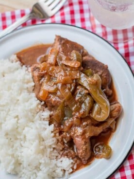 close up of ribs with bell peppers and onions on plate with white rice